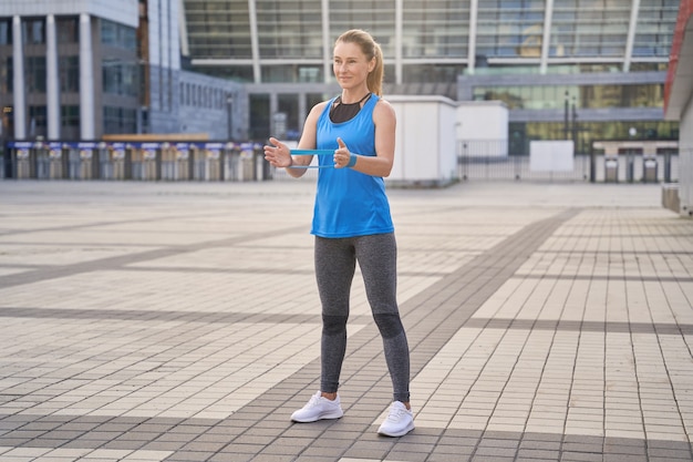 Ganzaufnahme einer lächelnden sportlichen Frau in Sportbekleidungstrainerin, die ein Widerstandsband hält, während