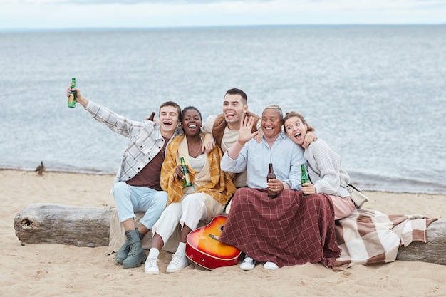 Ganzaufnahme einer verschiedenen Gruppe von Freunden, die im Herbst am Strand campen und für Fotos posieren