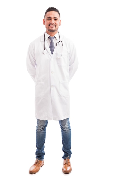 Ganzaufnahme eines jungen männlichen Doktors mit einem Laborkittel und einem Stethoskop gegen einen weißen Hintergrund
