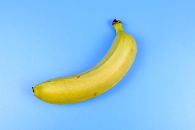 Ganze gelbe Banane auf blauem Hintergrund isoliert