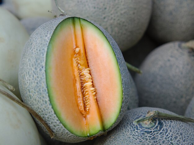 Ganze und abgeschnittene Scheibe japanischer Melonen, frische Orangenmelone oder Melone zum Verkauf auf dem Bauernmarkt.