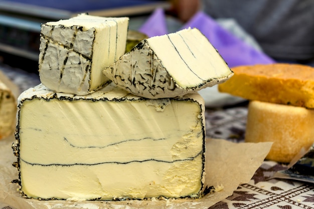 Ganze und gekerbte Köpfe verschiedener Käsesorten am Markt. Konzept des Käses