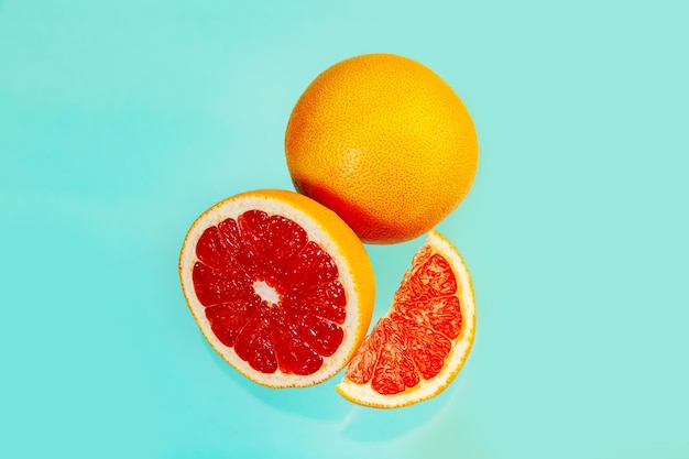 Ganze und geschnittene saftige Grapefruits auf hellblauem Hintergrund Lebensmittelhintergrund