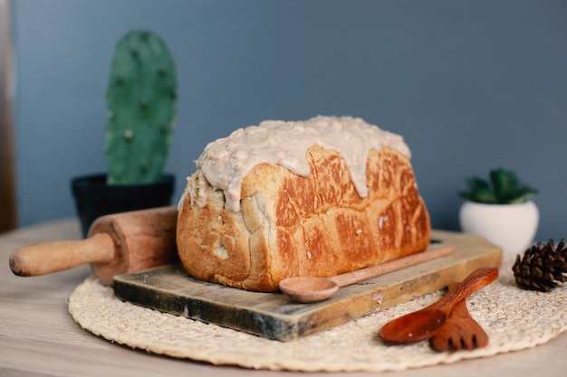 Ganzer Laib Brot auf Holzbrett mit Topping-Sauce oben drauf