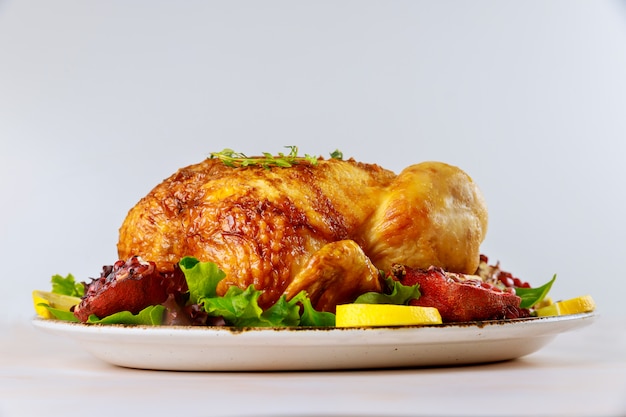 Ganzes Brathähnchen auf Teller mit Salat und Granatapfel