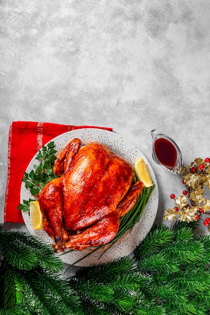 Ganzes gebackenes Huhn oder Truthahn in einer Soße mit Paprika auf einem Teller und einer weihnachtlichen Tischdekoration, vertikales Foto mit Kopienraum für Text. Foto in hoher Qualität