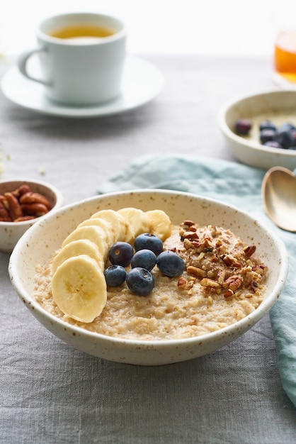 Ganzes Haferflocken, große Schüssel Brei mit Banane, Beeren, Nüssen zum Frühstück. Seitenansicht, vertikal