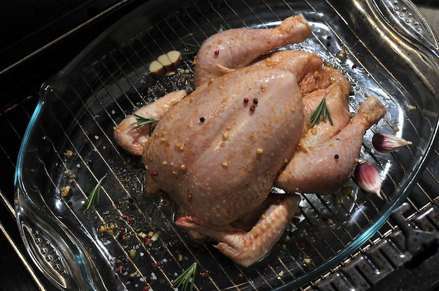 Ganzes rohes Huhn in einer Glasschale auf dem Grill im Ofen