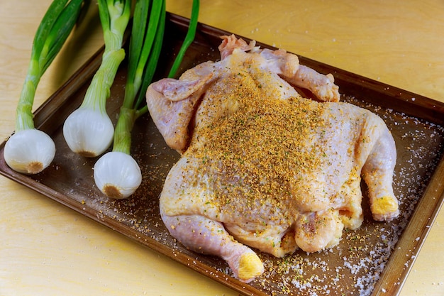Ganzes rohes Huhn in Eisenpfanne mariniert und bereit zum Kochen mit Zutaten zum Kochen auf Steinrücken
