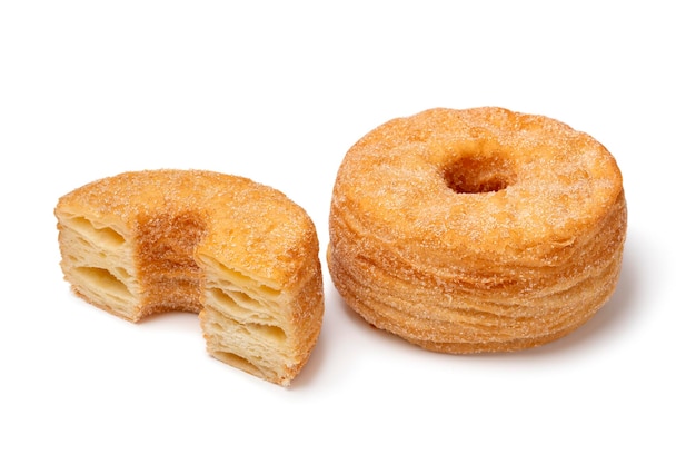 Ganzes und halbiertes schmackhaftes süßes Zimt Cronuts isoliert auf weißem Hintergrund