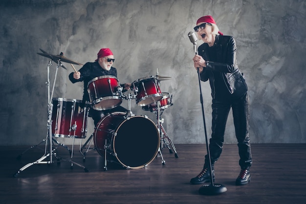 Ganzkörper der alten Dame Mann Rockband Konzert spielen Trommel singen