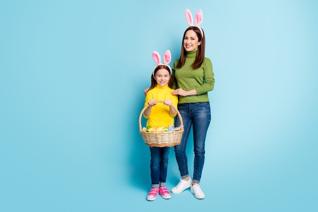 Ganzkörperansicht in voller Länge von schönen attraktiven, schönen, fröhlichen, fröhlichen Mädchen, die den festlichen Festkorb April tragen, isoliert über der leuchtend blauen Farbe des hellen, lebendigen Glanzes