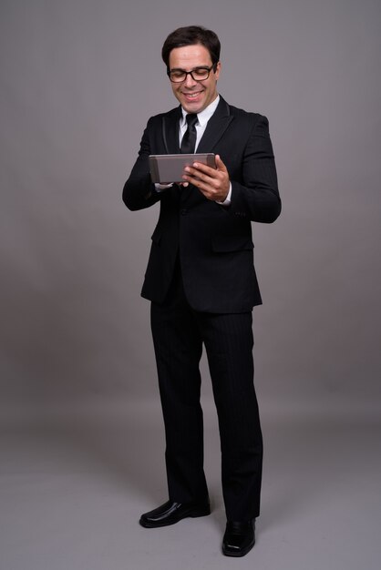 Ganzkörperaufnahme des Geschäftsmannes im Anzug unter Verwendung der digitalen Tablette