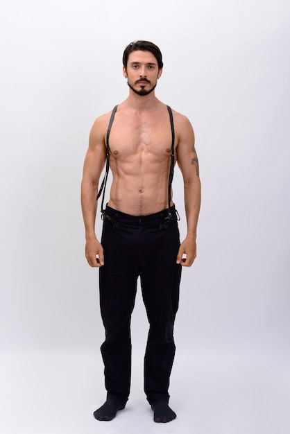 Ganzkörperaufnahme des gutaussehenden muskulösen Mannes mit den stehenden Hosenträgern