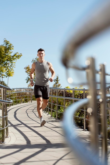 Ganzkörperaufnahme eines Mannes in Sportbekleidung, der im Sommer läuft und geradeaus schaut