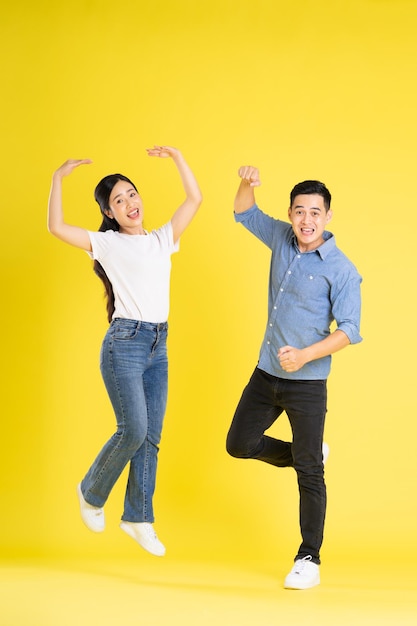 Ganzkörperbild eines asiatischen Paares, das auf gelbem Hintergrund posiert