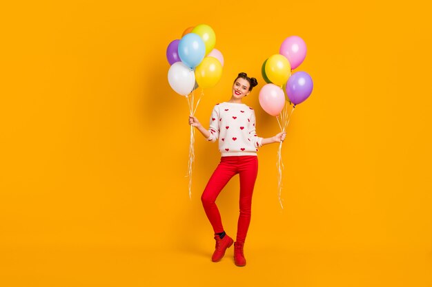 Ganzkörperfoto der hübschen Dame bringen viele bunte Luftballons Überraschung Party Freunde Ereignis tragen Herzen Muster Pullover