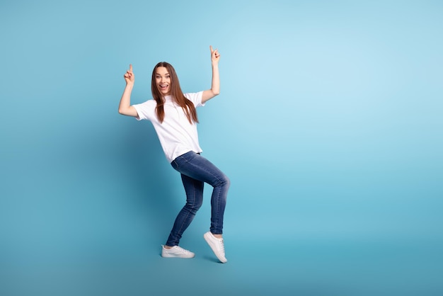 Ganzkörperfoto der jungen hübschen Dame zeigt Finger leeren Raum Promo-Tanzen isoliert über blauem Hintergrund