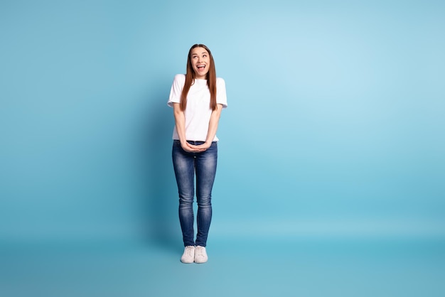 Ganzkörperfoto einer jungen charmanten Frau, die sich wundert, wie ein leerer Raum aussieht, tragen legere Kleidung, die über blauem Hintergrund isoliert ist