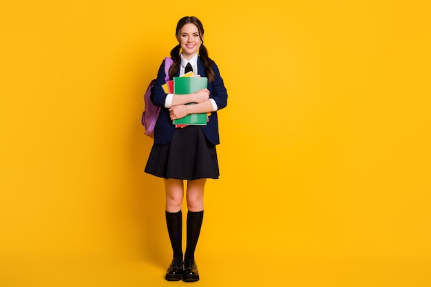 Ganzkörperfoto eines positiven A-Level-Studentenmädchens, das Notizbücher hält