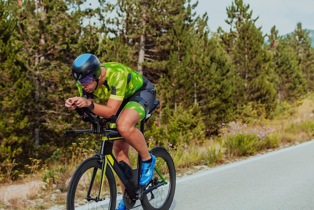 Ganzkörperporträt eines aktiven Triathleten in Sportbekleidung und mit Schutzhelm auf dem Fahrrad. Selektiver Fokus.