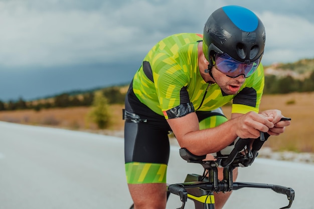 Ganzkörperporträt eines aktiven Triathleten in Sportbekleidung und mit Schutzhelm auf dem Fahrrad. Selektiver Fokus.