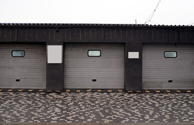Garagenrollos. geschlossene Autowaschanlage, automatisches elektrisches Rolltor oder Push-up-Tür. Fensterladen oder Rolltor und Backsteinmauer außen.