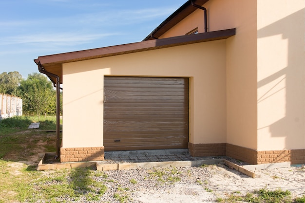 Garaje individual de nueva construcción con puerta enrollable cerrada anexa al borde de la construcción de una casa nueva