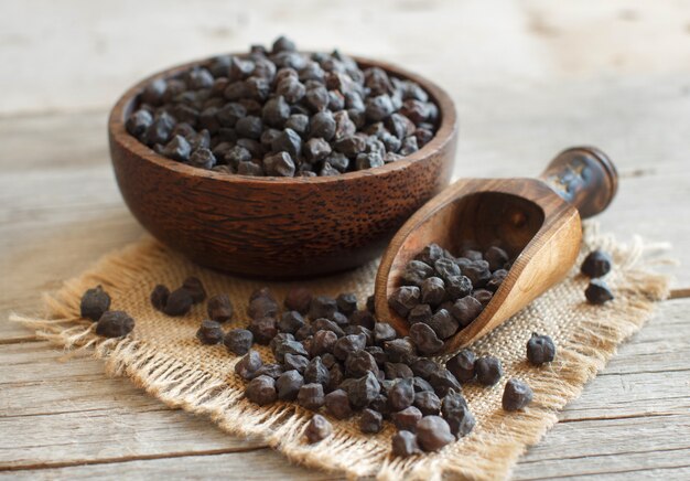 Garbanzo negro en un recipiente con una cuchara sobre una mesa de madera