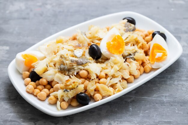 Garbanzos con aceitunas de bacalao y huevo cocido en plato blanco