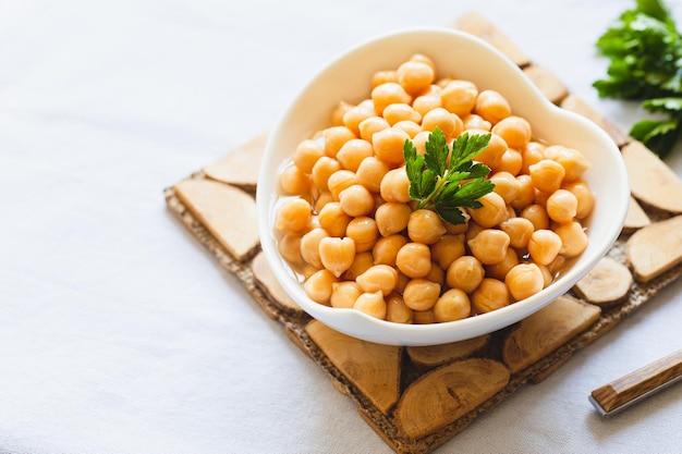 Garbanzos cocidos en tazón blanco Ingrediente para comida vegetariana sabrosa Enfoque selectivo de garbanzos hervidos