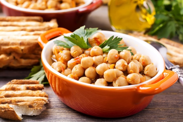 Garbanzos cocidos vegetarianos con tomate y perejil sobre fondo de madera vieja.