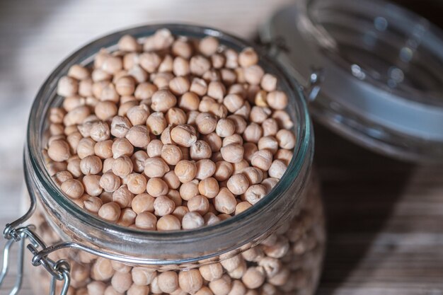 Garbanzos crudos en un frasco de vidrio sobre una tabla de madera vieja. Producto vegano saludable