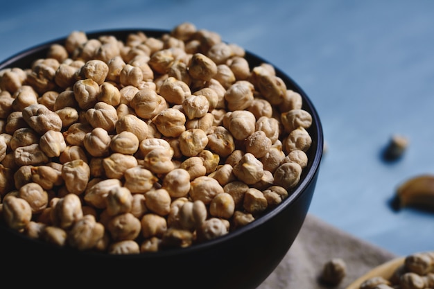 Garbanzos crudos en un tazón y cuchara de madera.