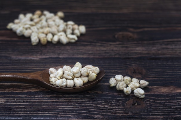 Foto garbanzos en una cuchara de madera sobre un fondo de madera oscura.