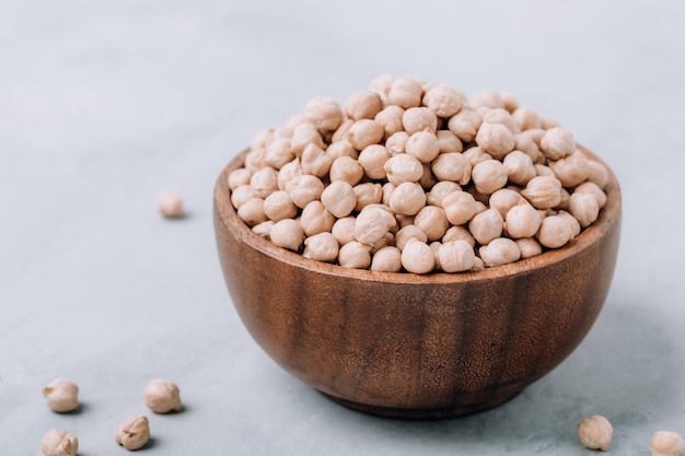 Garbanzos Frijoles de garbanzos orgánicos crudos en tazón de madera sobre fondo de piedra gris