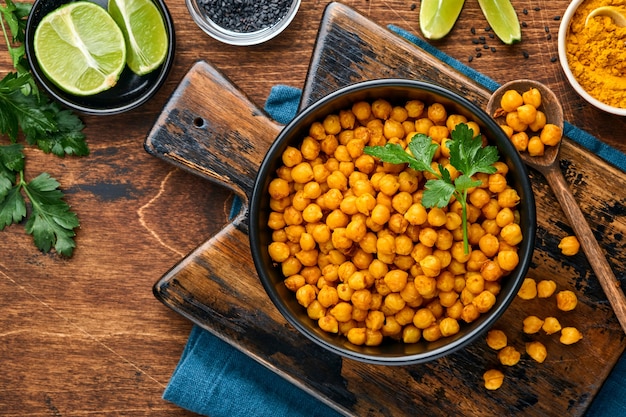 Garbanzos fritos con cúrcuma en plato de cerámica sobre un fondo de mesa de madera vieja. Garbanzos picantes asados o chana o chole de la India, receta popular de bocadillos. Vista superior.