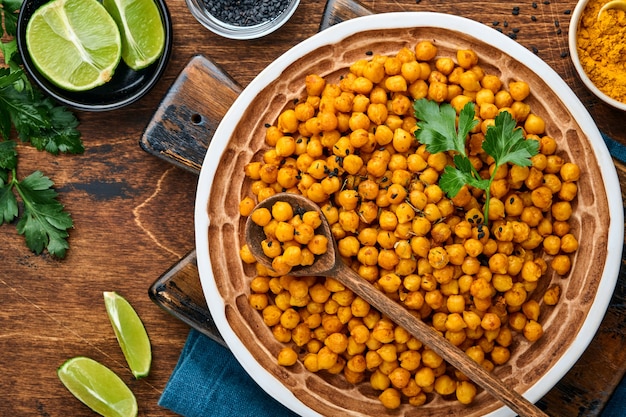 Garbanzos fritos con cúrcuma en plato de cerámica sobre un fondo de mesa de madera vieja. Garbanzos picantes asados o chana o chole de la India, receta popular de bocadillos. Vista superior.