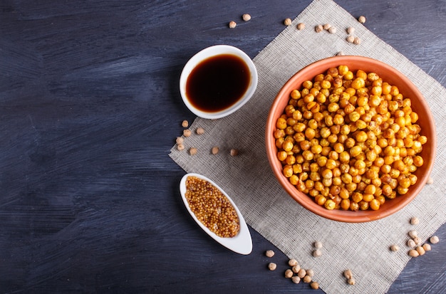 Garbanzos fritos con especias en un plato de arcilla sobre madera negra