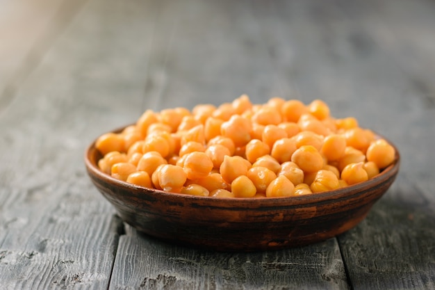 Garbanzos hervidos en un cuenco de la arcilla en una tabla de madera negra.