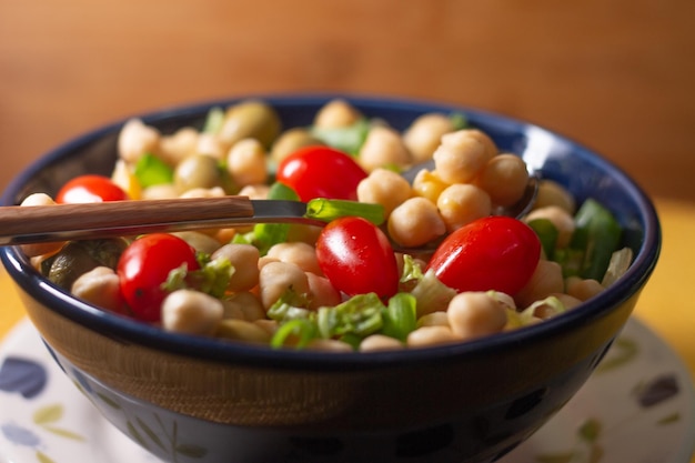 Garbanzos con hojas de aceitunas y tomates en un recipiente azul sobre la mesa