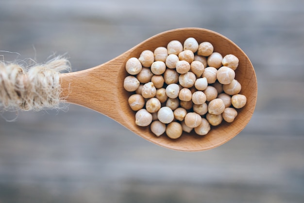 Garbanzos de legumbres secas crudas o garbanzos en cuchara rústica de madera sobre fondo borroso vegeta ...