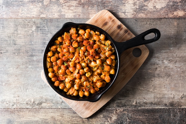 Garbanzos picantes fritos en sartén en vista superior de la mesa de madera