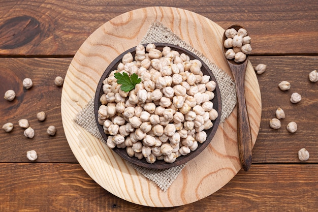 Garbanzos en un plato de madera, cuchara de madera sobre una base de madera Vista superior.