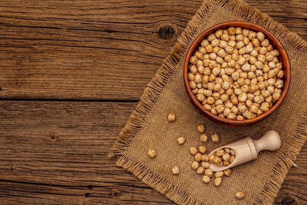 Garbanzos secos en un tazón de cerámica en la mesa de madera vieja. Ingrediente tradicional para cocinar hummus