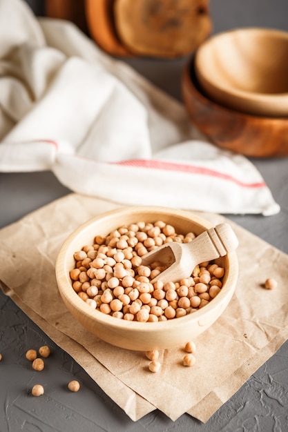 Garbanzos en un tazón de madera sobre fondo gris