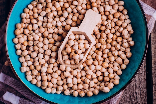 Garbanzos en un tazón sobre mantel con cuchara de madera en mesa de madera. Comida vegana saludable