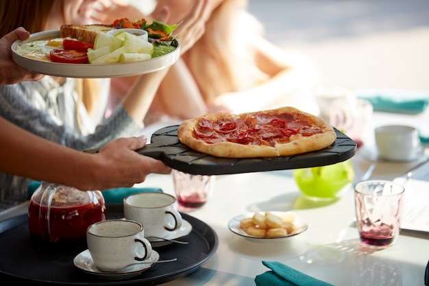 Garçom caseiro traz deliciosa pizza italiana para clientes em restaurante