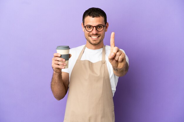 Garçom de restaurante brasileiro sobre fundo roxo isolado mostrando e levantando um dedo