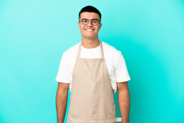 Foto garçom de restaurante rindo sobre parede azul isolada